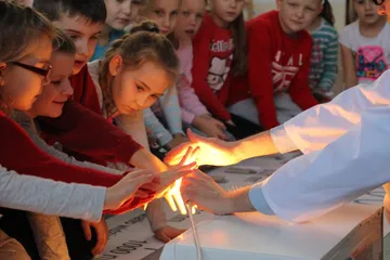 Dzieci wyciągają ręce do świecącej lampy