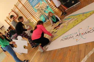 Dzieci układają duże puzzle z logo Fundacji