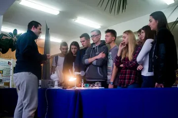 Uczniowie przy stole z doświadczeniem z lampą