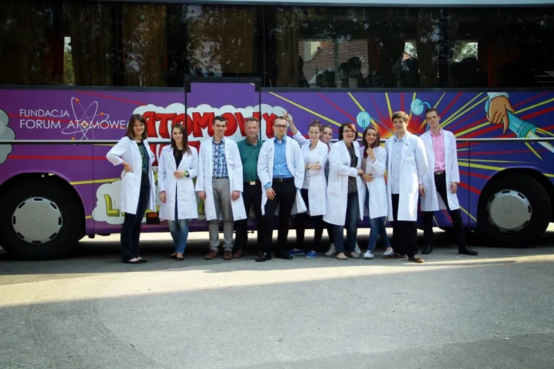 Zespół 4. edycji w białych fartuchach przed fioletowym Atomowym Autobusem