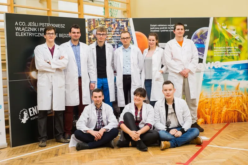 Zespół 5. edycji w białych fartuchach na tle plansz wystawy